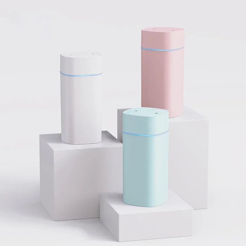 Three cylindrical devices in white, pink, and light blue on a white background