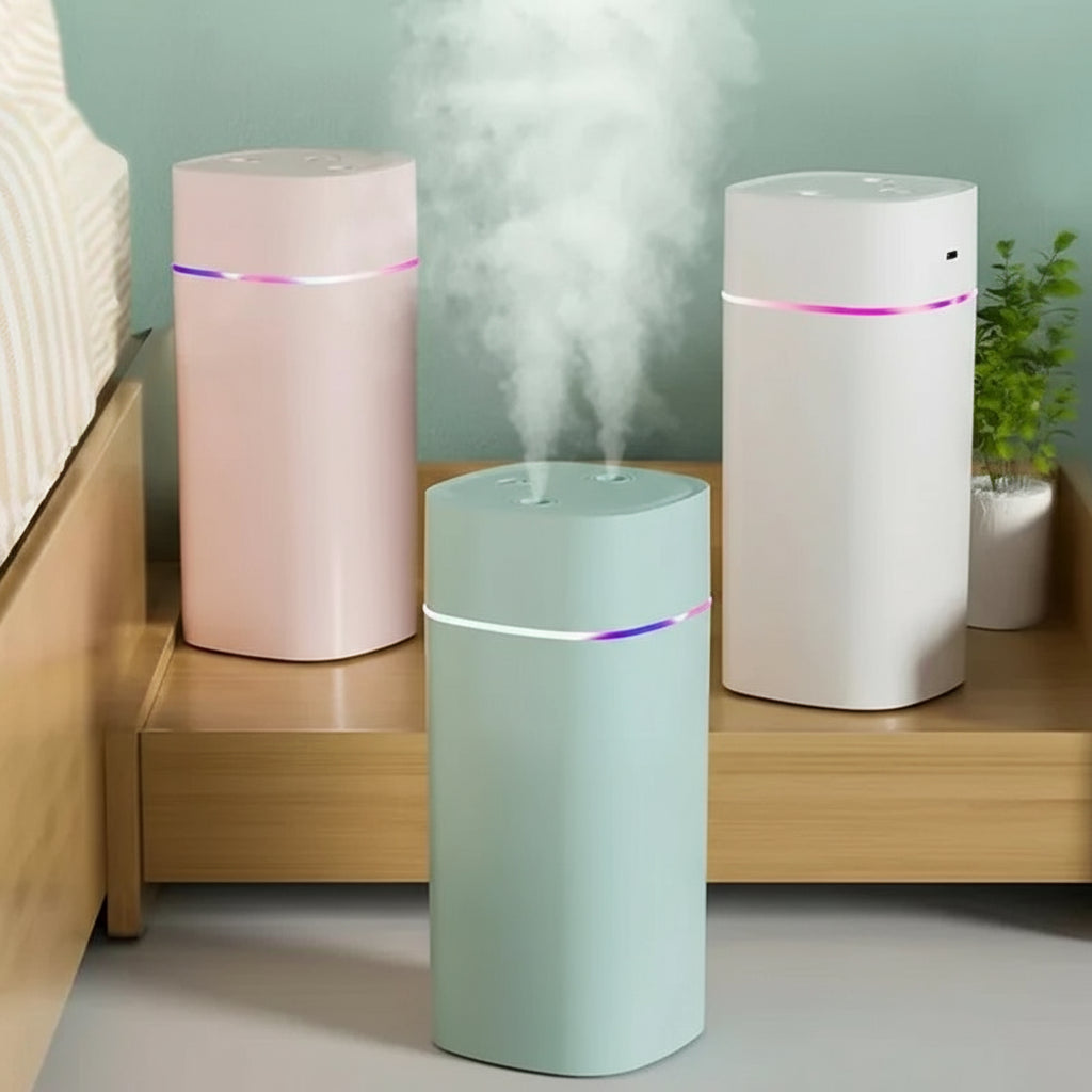 Three cylindrical humidifiers in pink, green, and white on a wooden surface with text indicating capacity and usage instructions.
